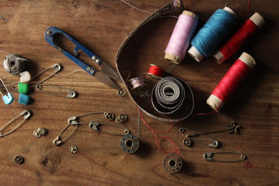A vibrant collection of sewing supplies including threads, scissors, pins, and tape on a w
