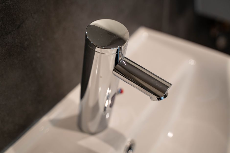 Close-up of a sleek stainless steel faucet on a ceramic sink, modern bathroom style.