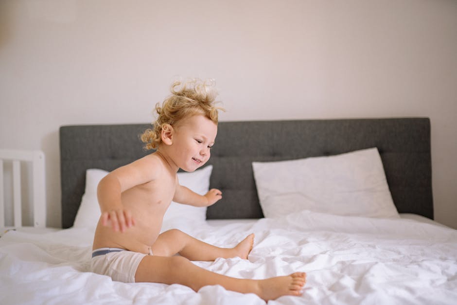 Smiling child energetically jumping on a bed in a cozy, well-lit bedroom, exuding joy.