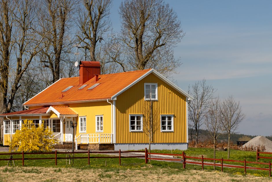 A picturesque yellow house with red roof in the Swedish countryside during spring.