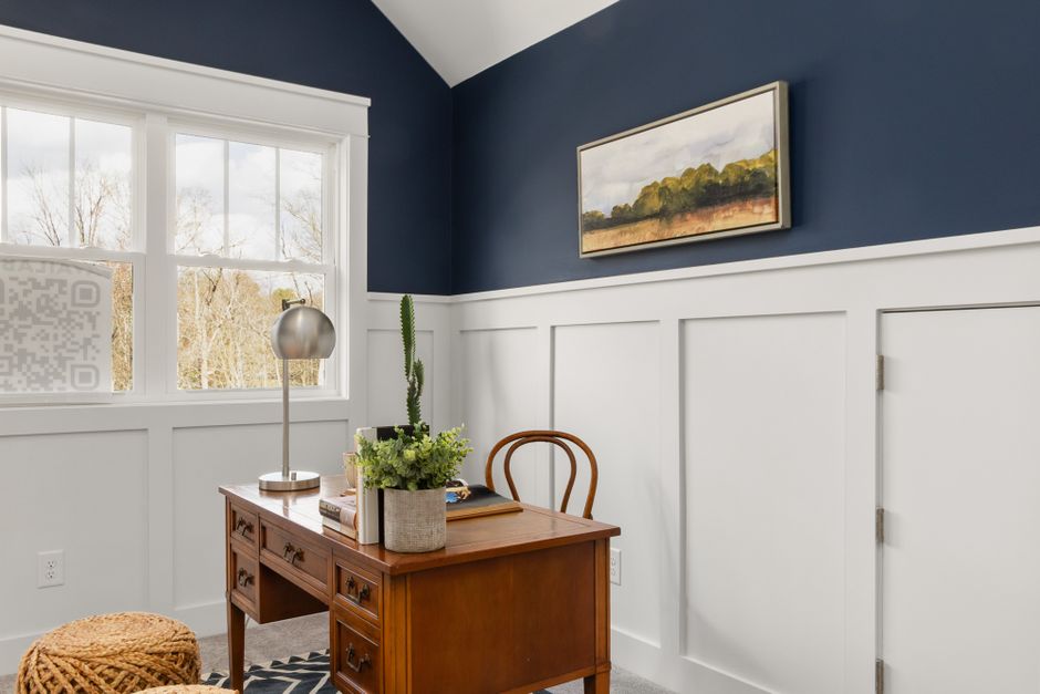 Stylish home office featuring a wooden desk, artwork, and modern decor in a bright, blue-walled room.