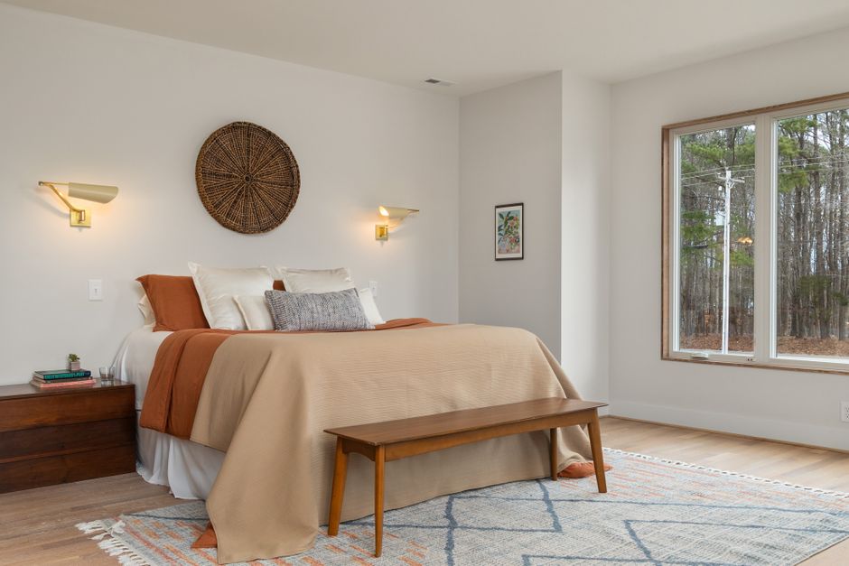 Elegant bedroom with wooden furniture and large windows offering natural light.