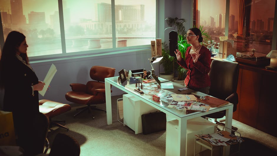 Two professional women engage in a business meeting in a modern Baghdad office with a view.