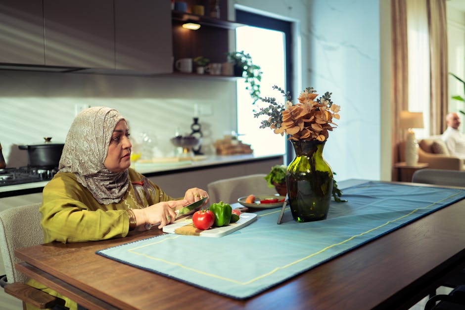 A Middle Eastern woman in a modern kitchen chopping vegetables. Bright ambiance, with flowers on the table.