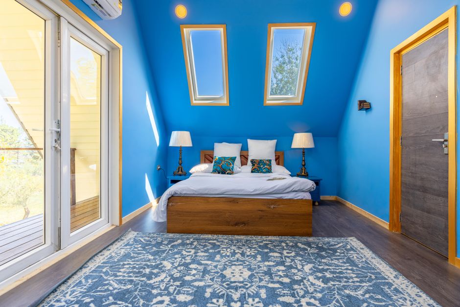 Inviting attic bedroom with skylights, blue walls, and cozy decor.