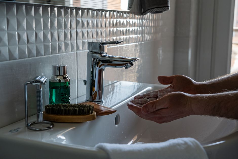 Close-up of handwashing with soap at a modern sink, emphasizing hygiene.