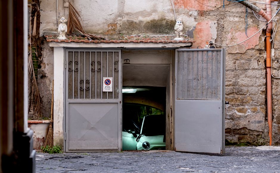 A classic car partially visible inside a rustic garage in Campania, Italy.