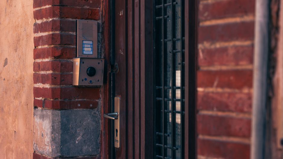 Close-up of a brick wall with a security intercom and door handles in Toulouse, France.