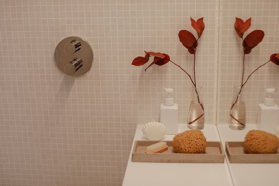 Stylish bathroom vanity with sponge, vase, and natural leaves in a minimalist setting.