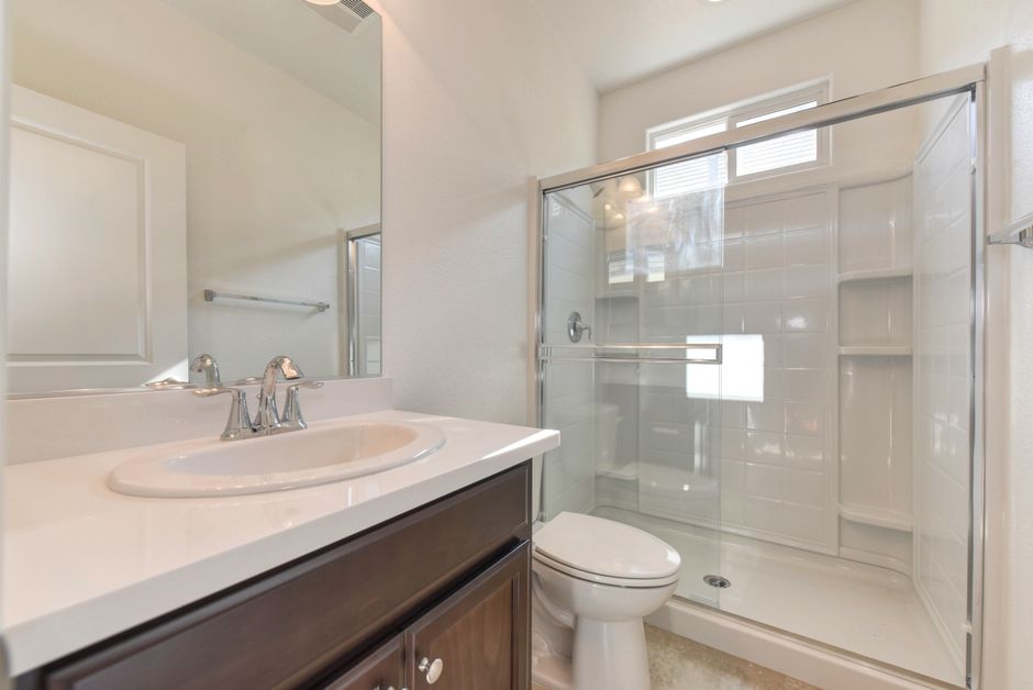 Bright modern bathroom featuring a shower, sink, and mirror in minimalist design.