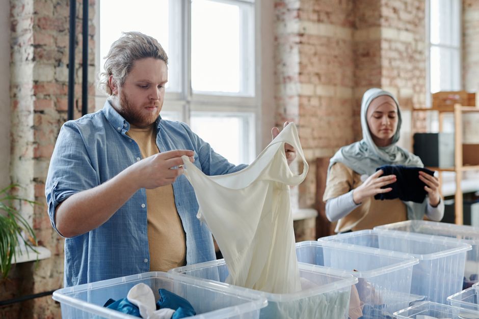Two diverse volunteers sorting donated clothes in an urban loft setting.