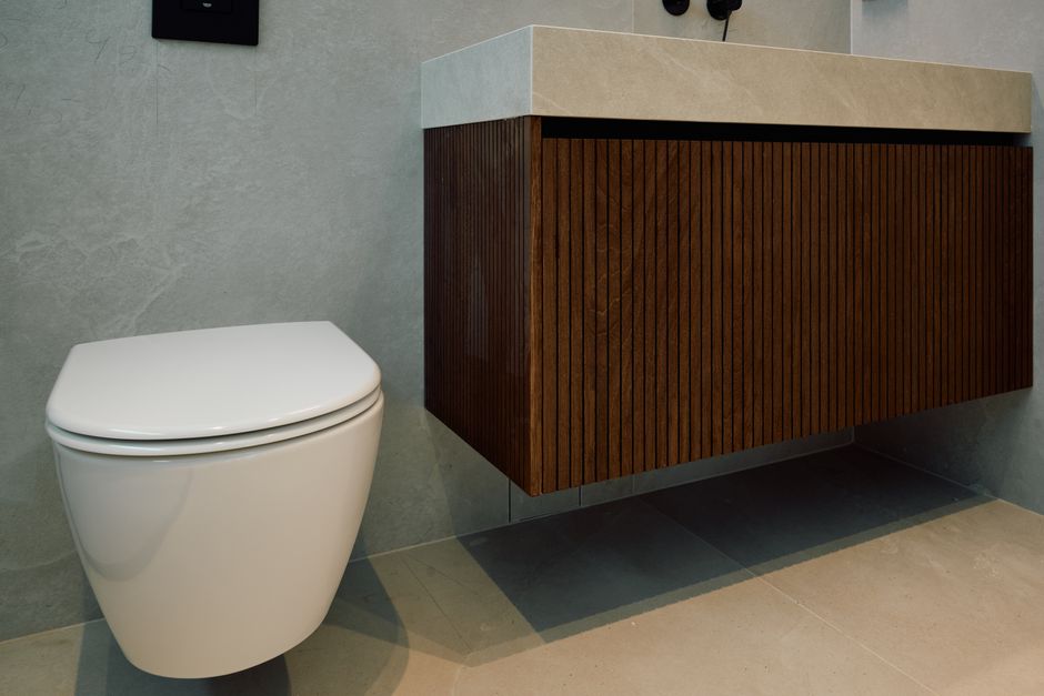 Stylish bathroom featuring a modern toilet and wood-paneled vanity cabinet.