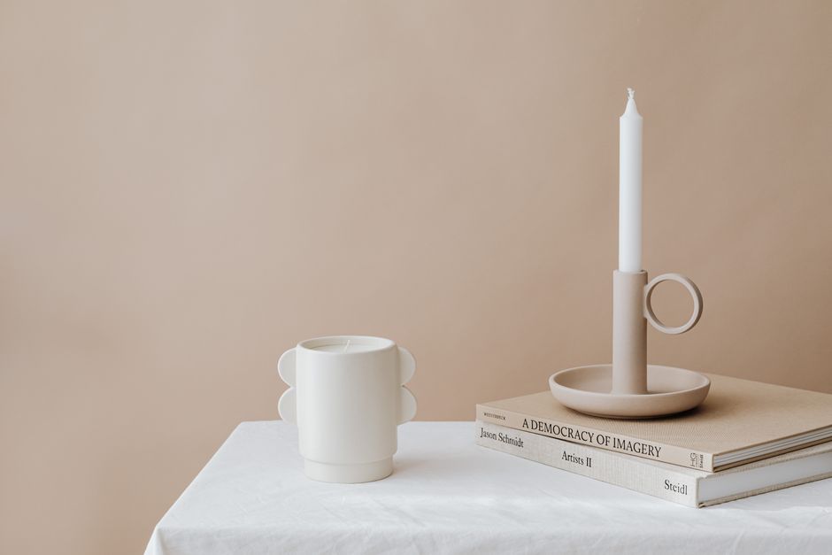 Elegant still life with candleholder, mug, and books on a beige backdrop. Perfect for minimalist decor.