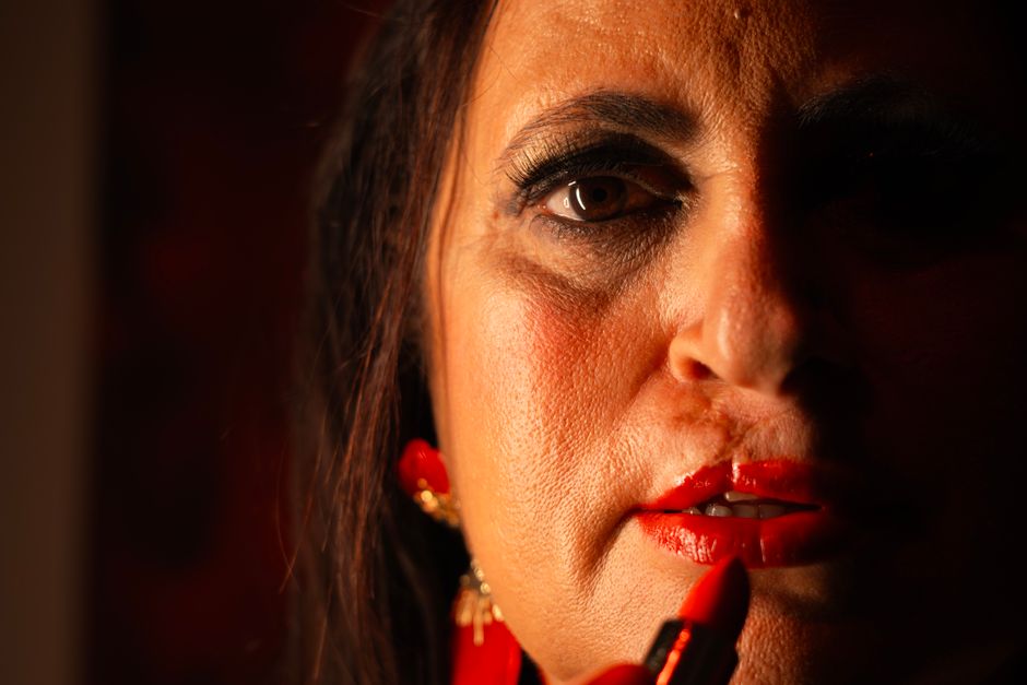 Close-up portrait of a woman applying red lipstick, illustrating beauty and self-expression.