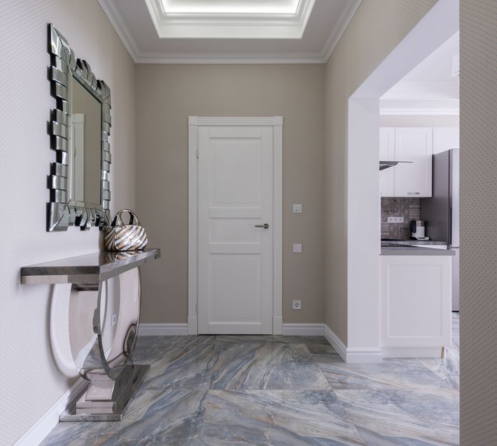 Passage interior with table under mirror against kitchen furniture on marble floor in cont