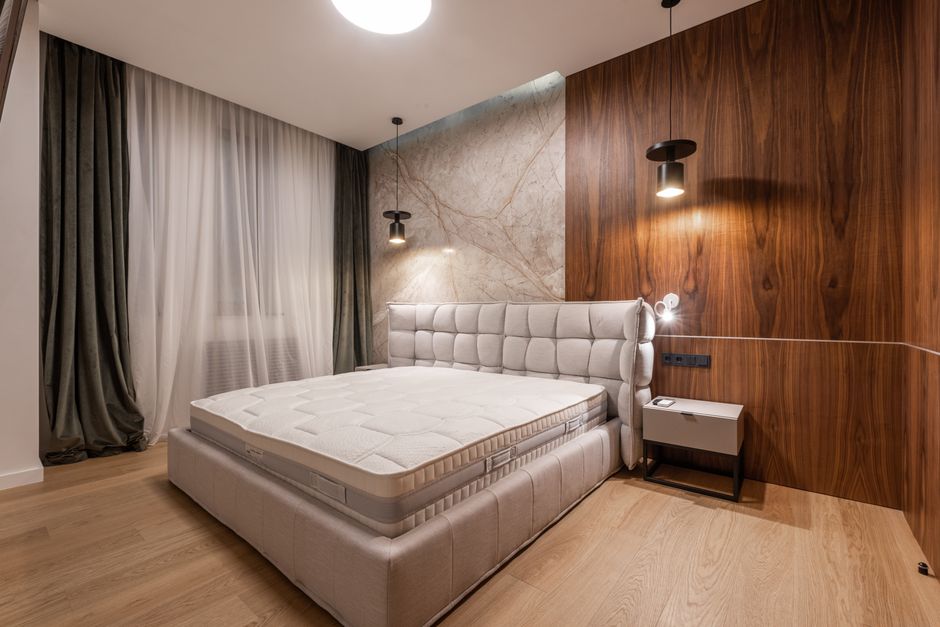 Comfortable soft empty bed placed in stylish modern bedroom in contemporary apartment in minimalistic style