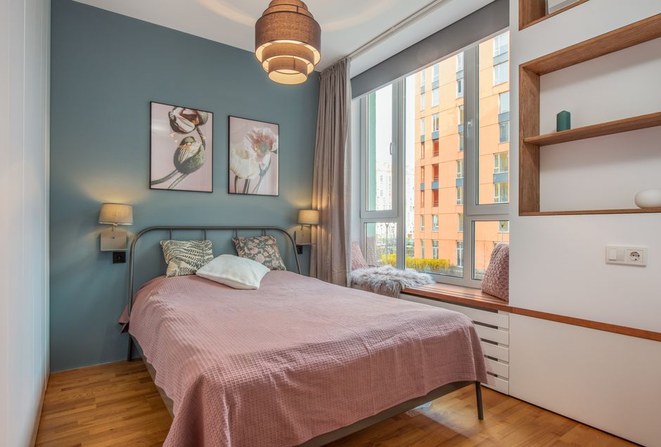 Comfortable bedroom with spacious soft bed and large window near wall with wooden shelves