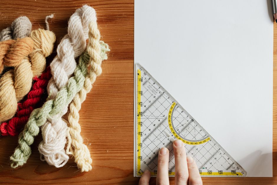 Top view of unrecognizable female weaver preparing template for future carpet on piece of 