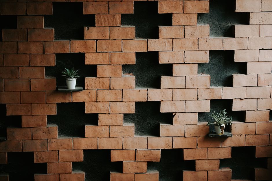 A geometric brick wall with potted plants on shelves for a simple decor look.