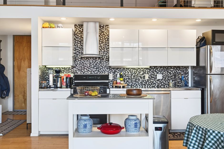 Luxury kitchen interior in a Boston apartment featuring a sleek mosaic backsplash, white cabinets, and modern appliances.