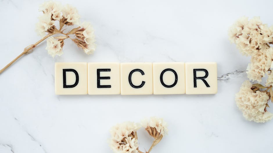 Stylish arrangement of letter tiles spelling 'decor' with dried flowers on a marble surface.